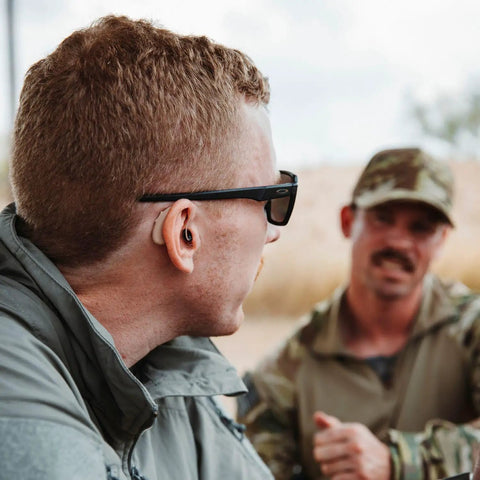 Man wearing Ion Pro 2 Bluetooth Rechargeable OTC Hearing Aids with App Control, UV Cleaning, and Enhanced Streaming Audio outdoors.