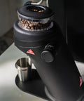 Game Changing Single Dose Coffee Grinder With 64 Millimeter Flat Burrs Stepless Adjustment, black finish, coffee beans in hopper.
