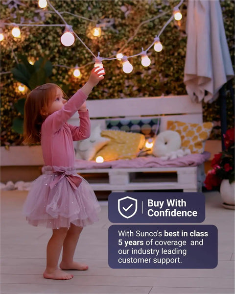 Young girl in pink dress reaching for string lights, garden setting, Sunco lighting promotion with Buy With Confidence text