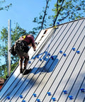 Worker using heavy-duty roof safety anchor on steep metal roof for first man up and last man down, 5,000-lb capacity.