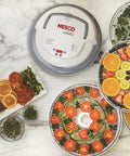 Digital Food Dehydrator With Smooth Adjustable Temperature And Even Heating For Whipping Up Homemade Beef Jerky Dried Fruit Fresh Herbs And Crispy Snacks On Four Stackable Trays In A Sleek Gray Design displaying sliced fruits and herbs on trays.