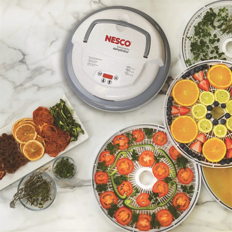 Digital Food Dehydrator With Smooth Adjustable Temperature And Even Heating For Whipping Up Homemade Beef Jerky Dried Fruit Fresh Herbs And Crispy Snacks On Four Stackable Trays In A Sleek Gray Design displaying sliced fruits and herbs on trays.