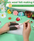 Hands using Ultimate Needle Felting Tool Kit For DIY Wool Projects With 60 Felting Needles And 68 Piece Set Including Foam Pad Wooden Handle Tool 8 Needle Heads Scissors Awl Snips And Finger Protectors Great Starter Kit on a foam pad with wool creations displayed.