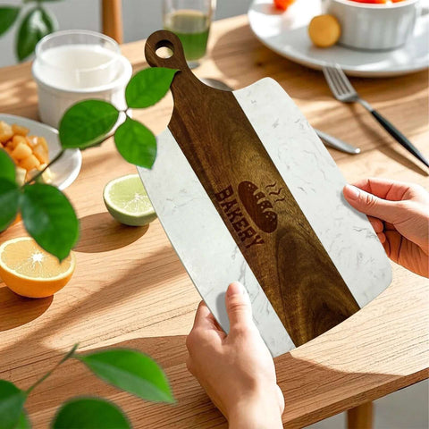 Cutting board with white marble panels and brown acacia wood center stripe, circular handle cutout.