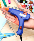 Person holding a blue hot glue gun from a 4 Piece Mini Hot Glue Gun Set With 20 Glue Sticks For Kids Projects Low Temp Kid Friendly Easy To Use Drip Proof Nozzle Rubber Protector Ideal For Arts And Crafts Sealing DIY Projects And Everyday Home Repairs against a background with craft materials.