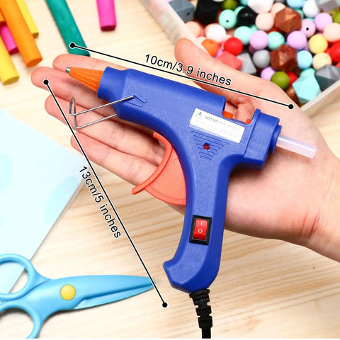 Person holding a blue hot glue gun from a 4 Piece Mini Hot Glue Gun Set With 20 Glue Sticks For Kids Projects Low Temp Kid Friendly Easy To Use Drip Proof Nozzle Rubber Protector Ideal For Arts And Crafts Sealing DIY Projects And Everyday Home Repairs against a background with craft materials.