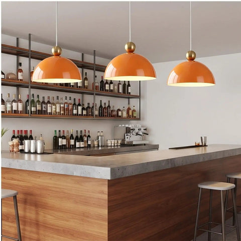 MIELPOXS Modern Dome Pendant Light Iron Metal Hanging Ceiling Fixture with orange dome shades hanging above a bar area.