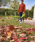 No Sweat Heavy Duty 18V Cordless Yard Leaf Blower With Comfy Overmold Grip in use on lawn, clearing colorful autumn leaves.