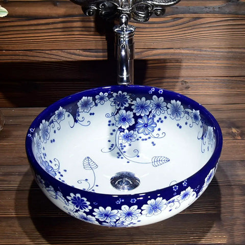 USZWBY Vessel Sinks Blue and White Porcelain Bathroom Basin Sink round ceramic sink with floral design on a wooden countertop.