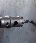 Close-up of 7 3/4 Inch Tungsten Carbide Tipped Hole Cutter drilling into steel, showing bit detail and precision cutting.