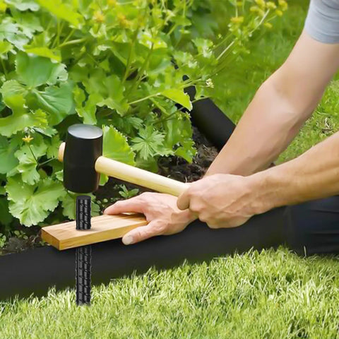 Man using hammer to drive 16 Inch Heavy Duty Rebar Stakes Set Of 16 Ground Anchors With Chisel Point for landscaping timber support.