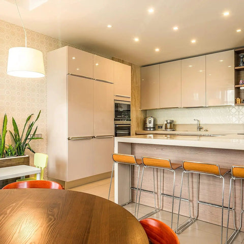 Modern kitchen with wooden table, bar stools at island, pendant lighting, and sleek cabinetry, showcasing contemporary design.