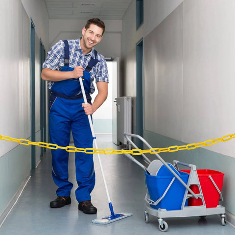 Man cleaning hallway with 200 ft yellow plastic chain barrier for crowd control and event decor blocking access