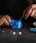 Hands using a screwdriver on a blue connector, surrounded by assorted electrical components and tools, showcasing DIY tech repairs.