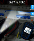 All In One Handy Clamp Meter Multimeter displaying AC voltage in a dimly lit electrical panel with flashlight and backlight features