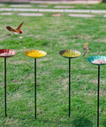 Four flower-shaped metal bird baths with metal stakes in a garden, each bath measures 7.1 inches in diameter and 1.3 inches deep.