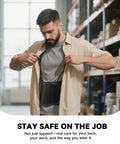 Man adjusting shirt over adjustable lower back support belt for heavy lifting and pain relief in warehouse setting.