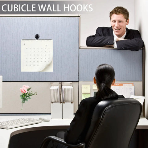 Office cubicle with calendar hung by Go To 20 Piece Metal Hook Set For Fabric Panel Cubicles And Walls, employee seated.