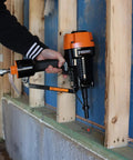 PSSCP 3 Inch Pneumatic Single Pin Concrete Nailer With Case in use on wood framing against concrete wall