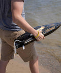 Person holding Heatwave Recoil 2 V2 26 Self Righting Brushless RTR RC Boat With Beast Power by the beach.