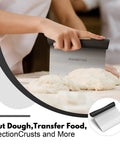 Person using Stainless Steel Bench Scraper With 1 To 6 Inch Measurement Marks For Even Dough Portions, Pastry And Pizza Cutter, Pro Grade Multi Purpose Kitchen Chopper For Veggies And Scraping Baked Sheets, Black on dough
