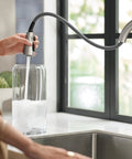 Top Shelf Stainless Steel Pull Down Kitchen Faucet Featuring One Handle High Arc Design with smooth spray hose filling a glass jar.