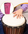 Heavy Duty Pro Kickass African Percussion Bag Crafted Using Washable Oxford Cloth Featuring Dense Impact Buffering And Reliable Cross Country Travel Design on a pink bag next to a hand on a djembe.