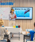 Teacher explaining water properties in classroom with 65 Inch 4K Interactive Touchscreen Monitor Smart Board Electronic Whiteboard Windows 11 Pro.