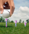 Hand placing golf ball on Durable Hardwood Golf Tees Three And One Quarter Inch Pack Of 100 In Pink And Blue For Women, unbreakable quality