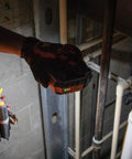 Rechargeable LED Work Light With 1000 Lumens, Magnetic Mount in a hand, used in a jobsite with visible pipes and tools.