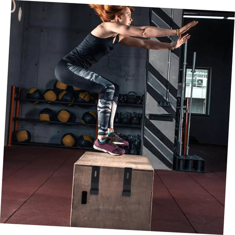 Person performing box jumps in a gym with rubber draw latch locks, concealed keeper on the wooden box surface
