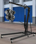 Heavy Duty Folding Engine Hoist And Cherry Picker Shop Crane lifting a car engine in a garage setting with six caster wheels.