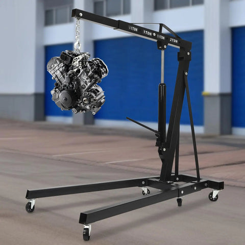 Heavy Duty Folding Engine Hoist And Cherry Picker Shop Crane lifting a car engine in a garage setting with six caster wheels.