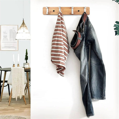 Slick Modern Wall Mounted Coat Rack In Brushed Brass With Heavy Duty Hooks For Entryway living room or kitchen holding striped towel and jeans.