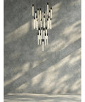 Modern 25 Light Crystal Pendant Ceiling Fixture With Matte Black Metal Frame And Contemporary Design For Indoor Living Spaces That Brings Straight Fire Vibes And Premium Swag hanging above textured gray wall.
