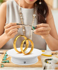 Spinning Electric Jewelry Display Rotating Turntable Adjustable Velocity Stand For Photo Shoots And Tabletop Showcase With Anti Skid Base with golden rings and jewelry.