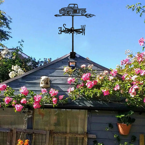 Black Metal Pickup Truck Weathervane Ornament on shed with pink flowers in garden; Outdoor Yard Decor Wind Direction Indicator