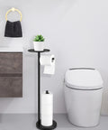 Free Standing Black Toilet Paper Holder Stand With Phone Shelf And Built In Storage, 4 Roll Capacity next to modern toilet.
