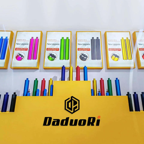 Front view of a DaduoRi drill bit display: yellow counter with logo and framed drill-bit posters, plus colorful cylinders.