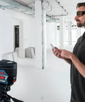 Pro Level 12V Green Beam Cross Line Laser With 100 Foot Reach And Smart Visimax Tech used by an operator controlling the device with a smartphone.