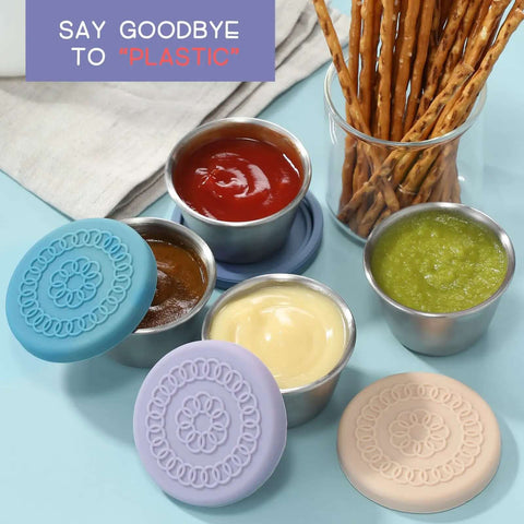 Eight Pack 2.4oz Stainless Steel Condiment Containers With Leakproof Silicone Lids displayed with sauces and snacks.