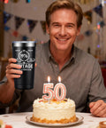 Man smiling with Born In 1976 Vintage 20 Oz Insulated Tumbler beside a birthday cake celebrating his 50th birthday.