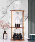 Portable Cold Brew Drip Tower Iced Coffee Maker with borosilicate glass and wooden stand for smooth chilled sipping.