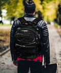 Man wearing the Dew Rose Print Unisex Backpack With Large Capacity For Everyday Carry, durable polyester, in a park setting