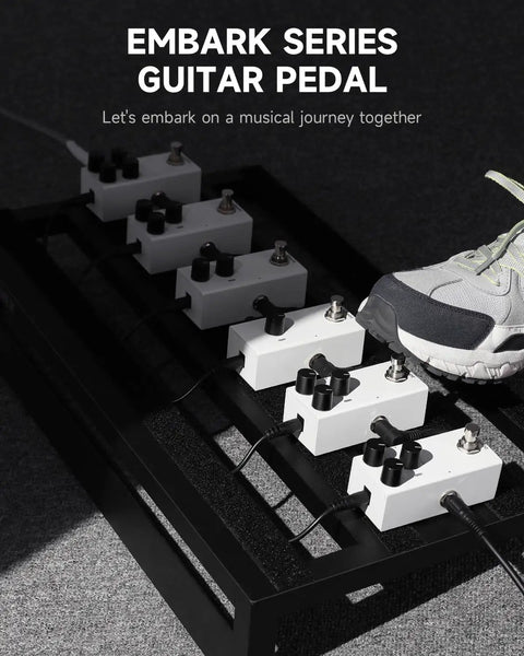 Person stepping on a row of Embark Series guitar pedals, each with multiple knobs, on a metal pedalboard.