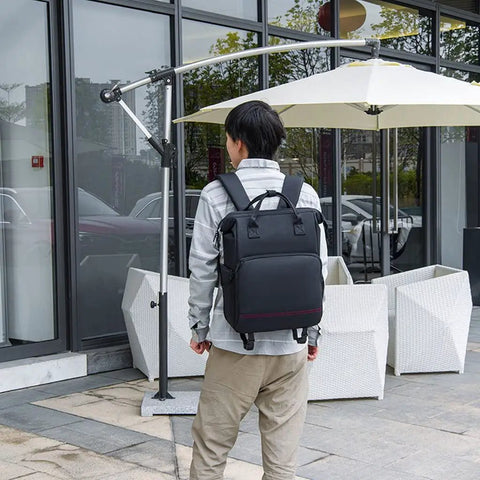 Person wearing DSLR Camera Backpack With Shockproof Shell outdoors, showcasing cushioned straps and sleek design for photography.
