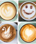 Four cups of latte art with various designs including a smiley face, swan, leaf, and heart.