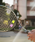 Tennis racket with Heart Shaped Tennis Dampeners Set Of 4 Silicone Vibration Absorbers in yellow and purple on strings