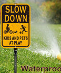 Slow Down Kids At Play Safety Signs in yellow and black reflective aluminum on grass with water spray illustration