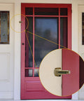 Built Tough Spring Loaded Screen Door Catch Slick Brass Finish Iron Frame keeps entryway secure on red door.
